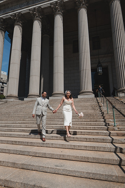 Bride and groom walking down the grand steps of the New York Supreme Court with columns behind — City Hall wedding portraits