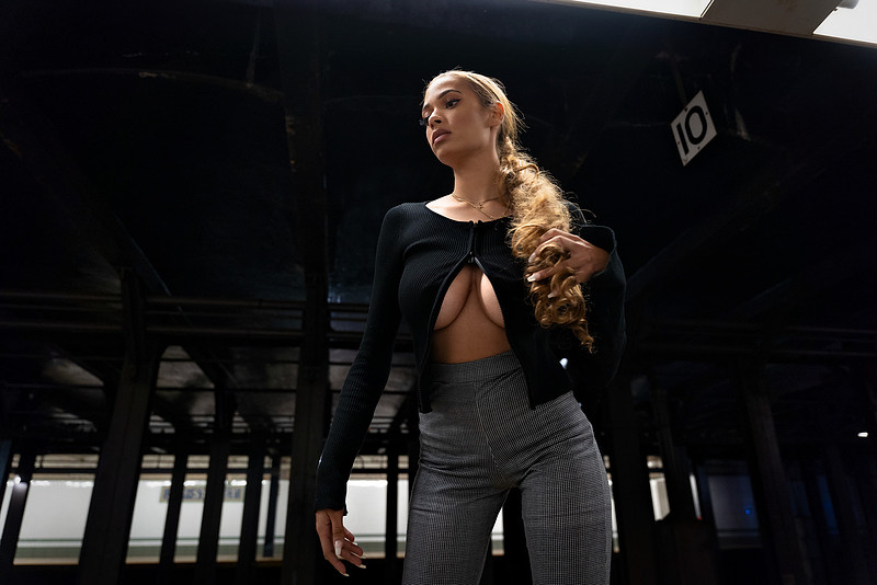 Close‑up of black heels stepping along the yellow tactile strip of a NYC platform.