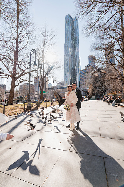 Couple framed by pigeons in flight in downtown Manhattan — playful City Hall portrait
