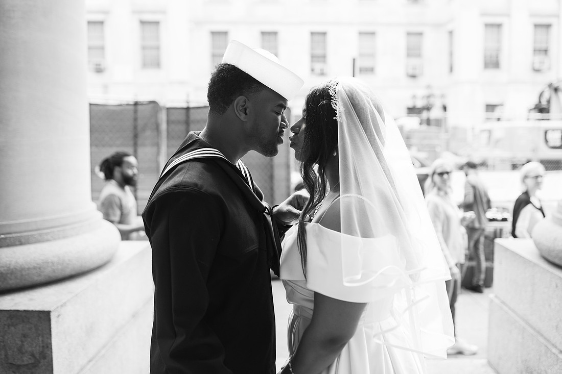 Navy groom and bride face-to-face, sharing a tender moment in front of NYC City Hall, captured in black-and-white.